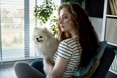 Young woman with dog sitting at home