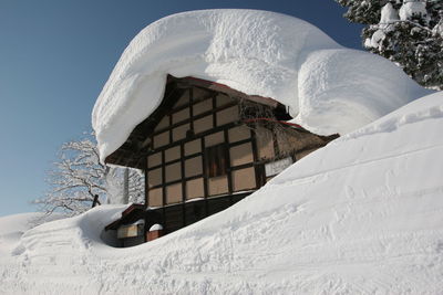 Low angle view of snow covered house against sky