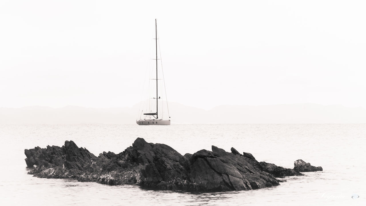 sea, water, sky, beauty in nature, rock, scenics - nature, rock - object, sailboat, tranquil scene, solid, nautical vessel, tranquility, nature, waterfront, no people, transportation, day, horizon, clear sky, horizon over water, outdoors