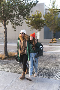 Mother and daughter crossing road pulling suitcase