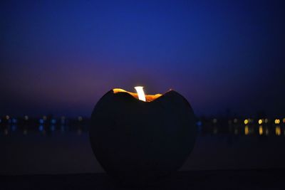 Close-up of illuminated candles against sky at night