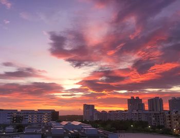 Cityscape against dramatic sky during sunset