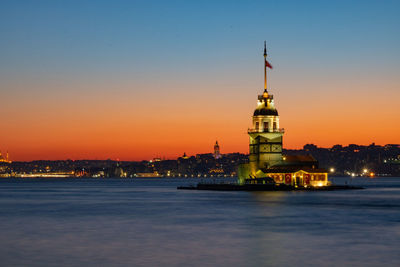 Illuminated building against sky during sunset