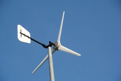 Low angle view of wind turbine against clear blue sky