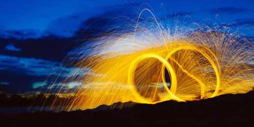 Light trails on water against sky at night