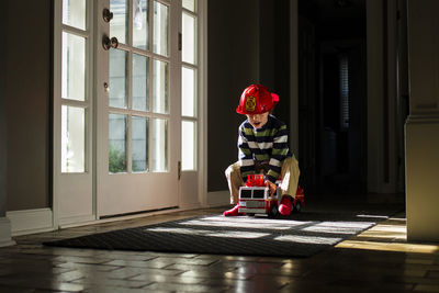 Playful boy driving toy fire engine at home