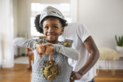 Father assisting cheerful boy in getting dressed as armor at home