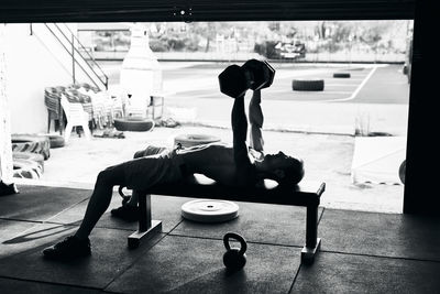 Shirtless fit young man working out in a garage with dumbells