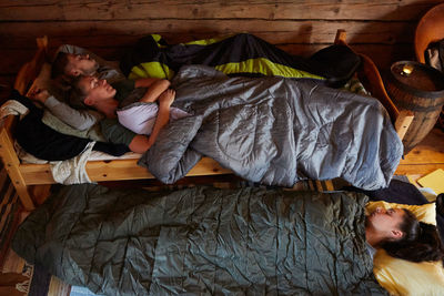 High angle view of male and female friends with blankets sleeping in cottage