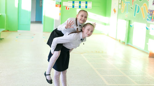 Portrait of girl carrying sister on back at classroom