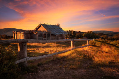 Abandoned house on field against sky during sunset