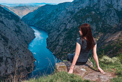 Woman sitting on rock looking at mountains