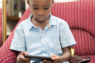 Child is very focus on his game in the mobile phone.