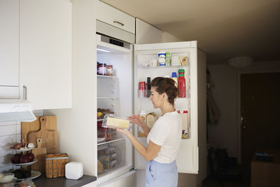 Woman standing in front of open fridge