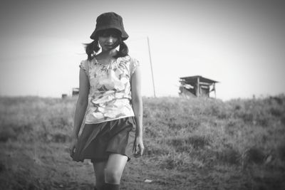 Young woman wearing hat while walking on field against sky