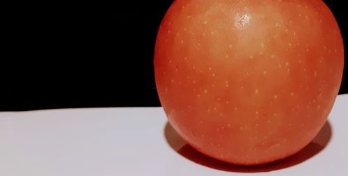 Close-up of orange slice on table against black background