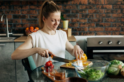 Young woman preparing vegetarian greens salad at home