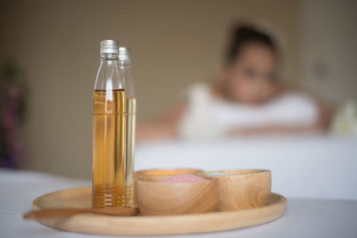 Close-up of spa product against young woman lying on massage table