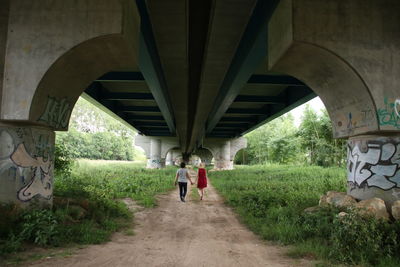 Rear view of people walking under bridge