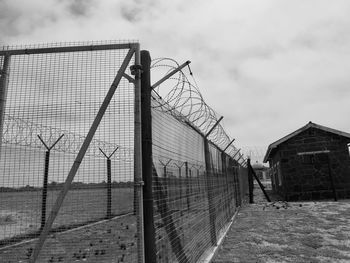 Metal fence by building against sky