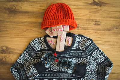 High angle view of warm clothing with christmas presents on wooden table