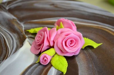 Close-up artificial pink roses on chocolate cake