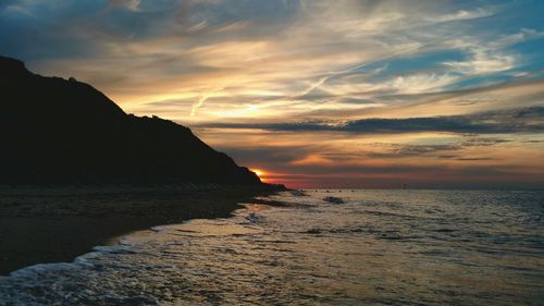 Scenic view of sea at dusk against cloudy sky