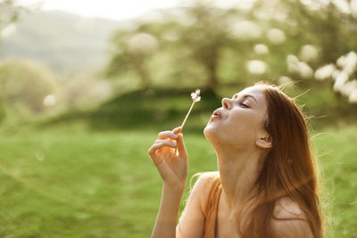Young woman blowing bubbles on field