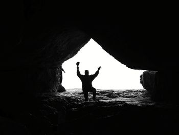 Silhouette man sitting in cave