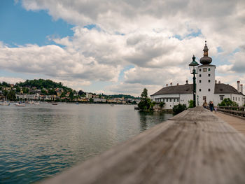 View of buildings by river against cloudy sky