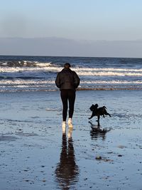 Rear view of people on beach against sky