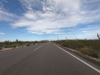 Road by trees against sky