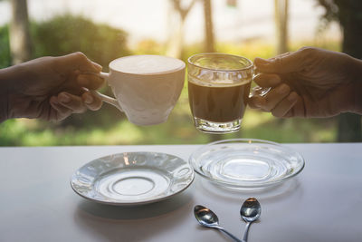 Midsection of person holding beer glass on table