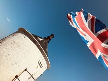 Low angle view of flags against clear blue sky