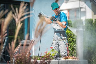 Man spraying water at backyard during sunny day