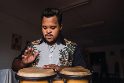 Black male musician in casual clothes sitting on chair with drums