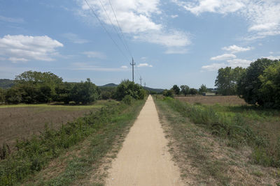 Road amidst field against sky