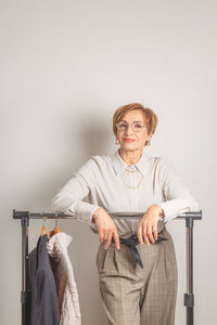 Portrait of young woman reading book while standing against white background