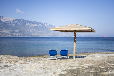 Chair on beach against blue sky