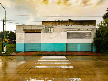 Empty road by building against sky during rainy season