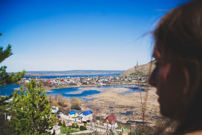 Rear view of woman by sea against clear blue sky