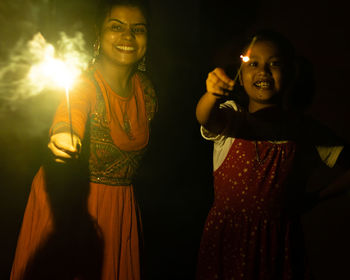 Indian girl child and her mother enjoying sparklers during diwali festival