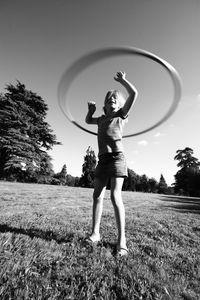 Full length of girl playing with plastic hoop on field