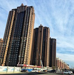 Low angle view of skyscrapers against cloudy sky