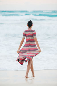 Woman with umbrella walking on beach