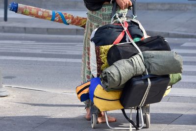 Low section of person with luggage cart on road