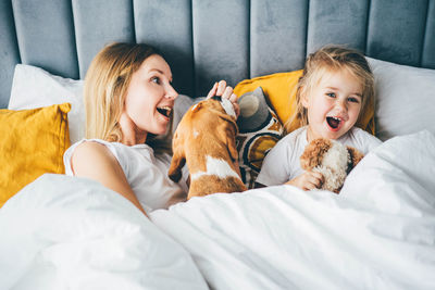 Portrait of woman with dog on bed at home