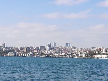 City at waterfront against cloudy sky