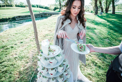 Young woman serving slice of cake at park