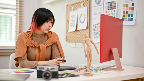 Young woman using laptop while sitting on table